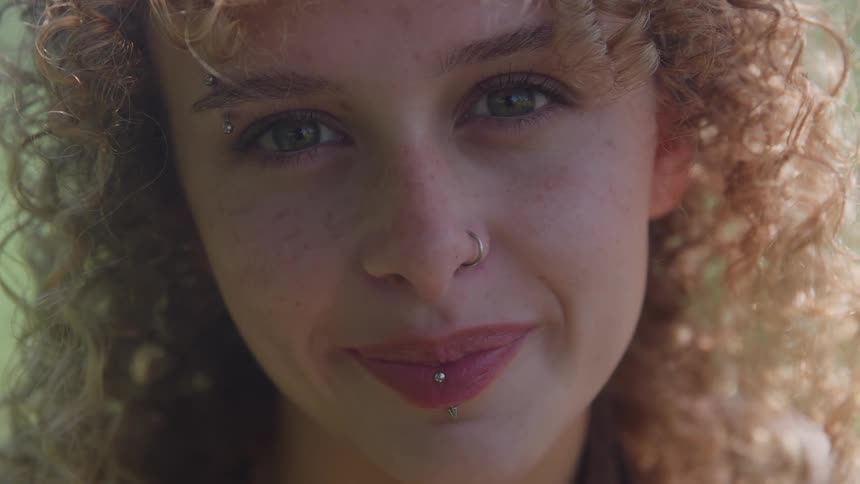 A close up of a young female smiling with very curly hair