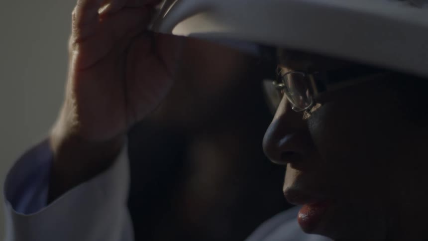 Older woman adjusting the fancy white hat she is wearing