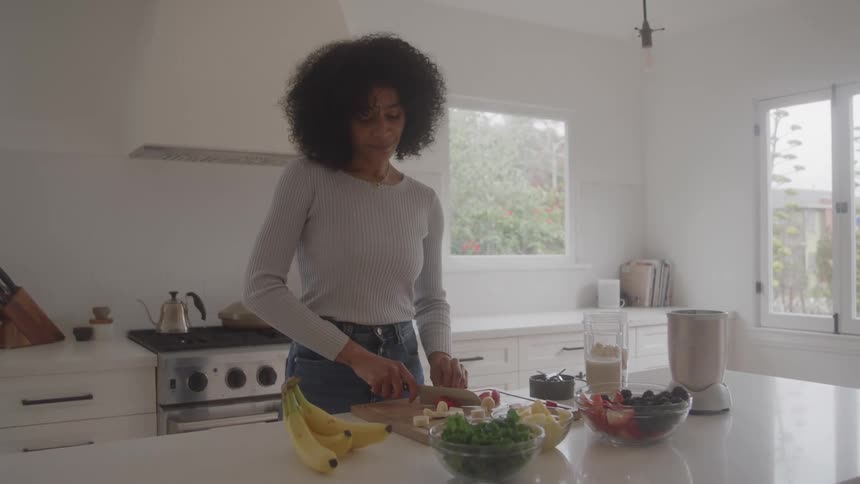 Woman standing at the kitchen counter slicing vegetables on a cutting board
