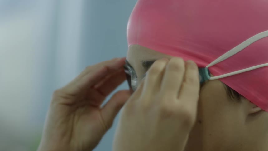 A woman puts on her swim goggles