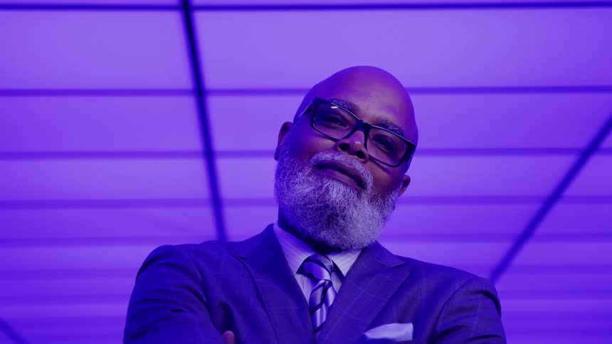 Man in a suit posing confidently under purple lighting