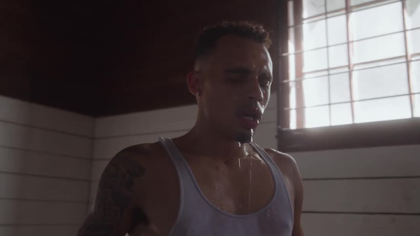 Close up of a young man hydrating after a fitness session indoors during daytime