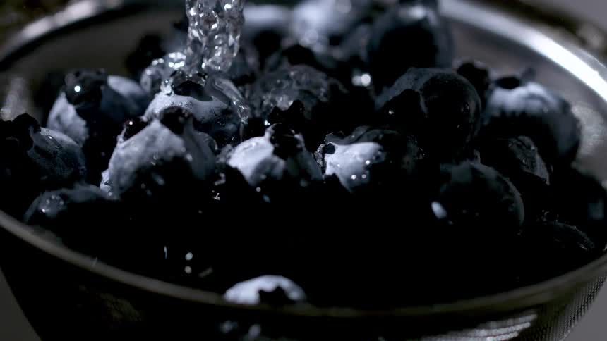 Blueberries being rinsed under a stream of water in the strainer