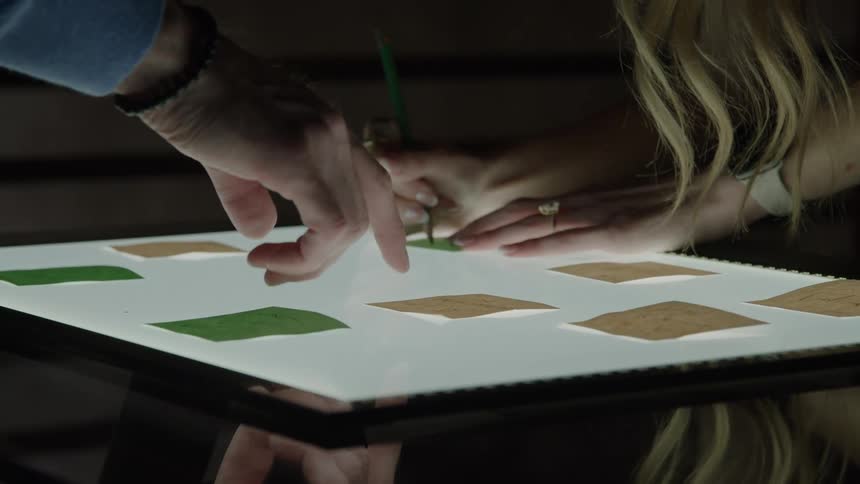 Close up of a man and woman filling sticky notes on a lit table indoors