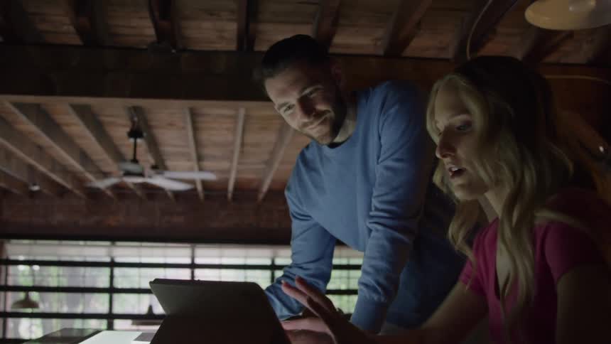 Man leaning over the table talking with a colleague in front of the tablet