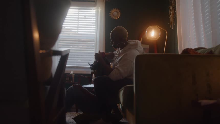 Black mother making her teenage daughters hair while sitting in the living room during daytime