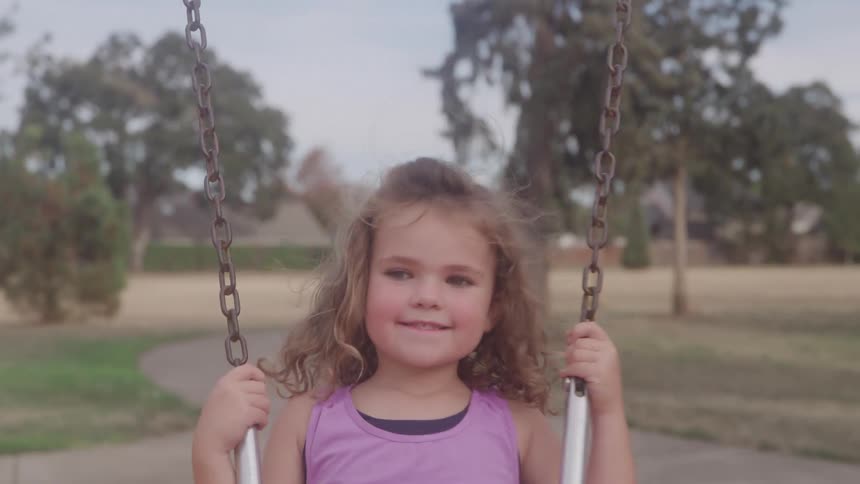 Girl smiling while swinging at the playground