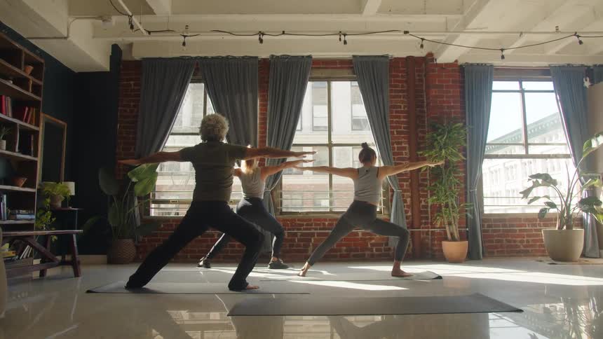 Group practicing yoga in a bright studio with large windows