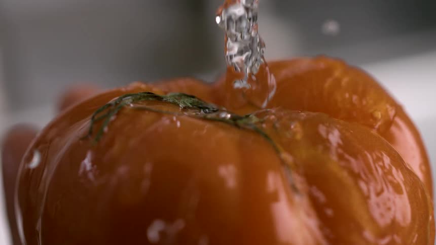 Tomato being washed under running water