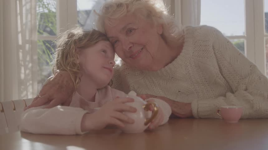 Grandmother and granddaughter sharing affection during a teatime play