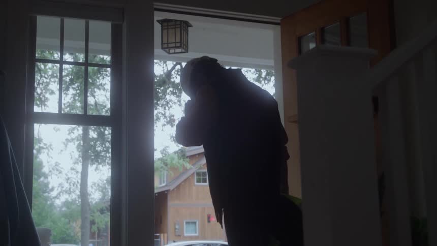 Man wearing hard hat exits residence at dusk