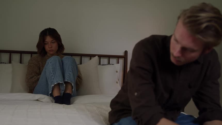 Two people sitting on bed