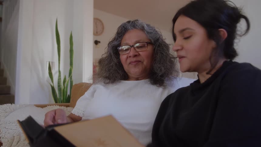 Two people browse an album in a residential room