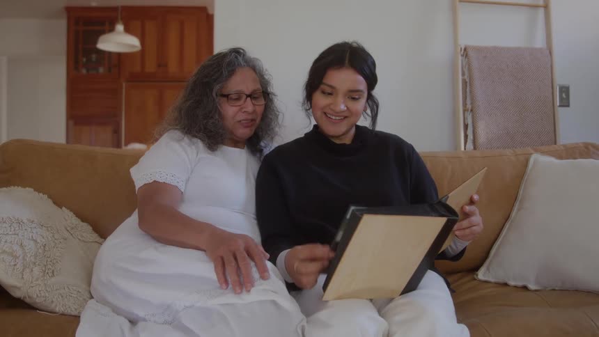 Two people sitting on a sofa are looking at a photo album