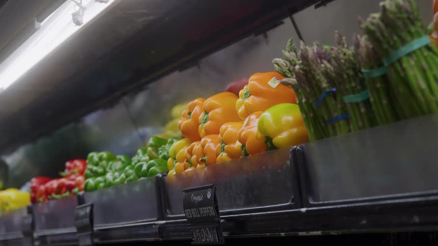 Person selects yellow bell pepper in organic produce section