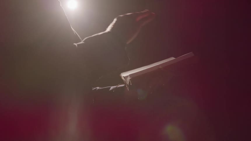 Person holds open book under dramatic lighting in dim setting