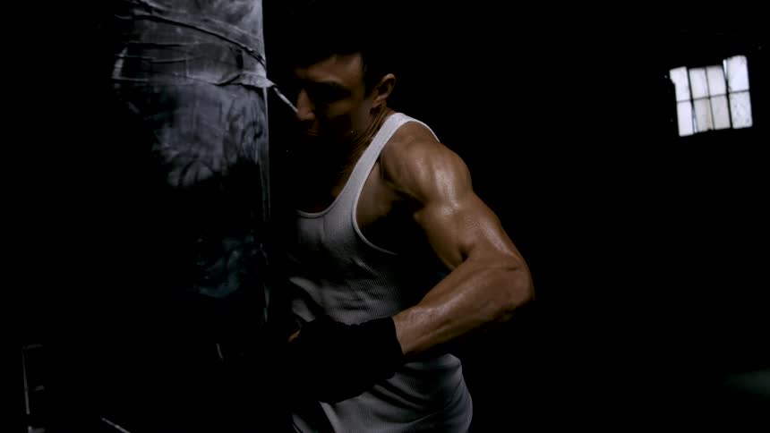 Fighter strikes a training bag in a dark setting