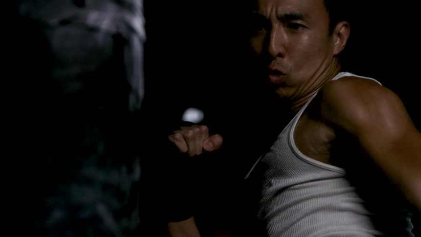 Man focused while performing a fighting strike in a dark setting