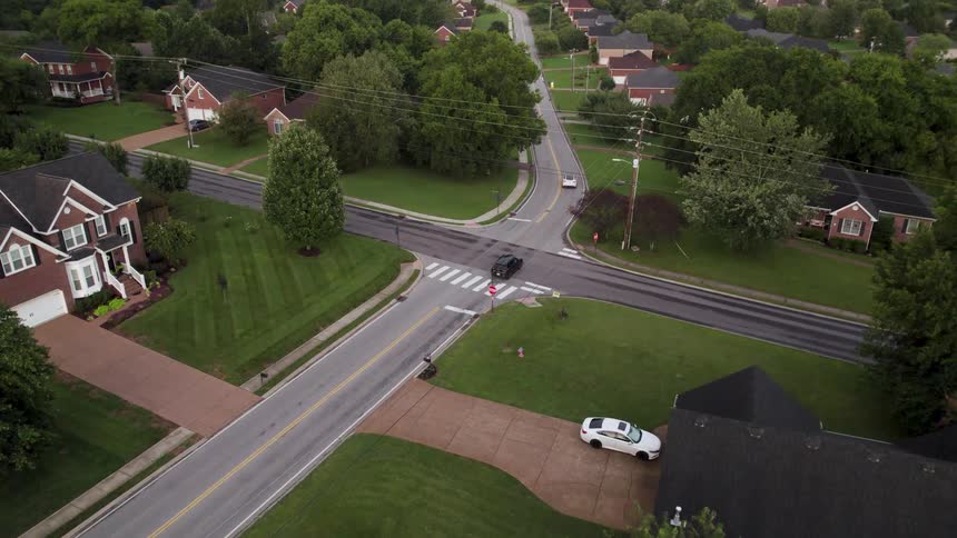 A suburban area stretches along the roadside with cars passing by homes and buildings line the street forming a neat backdrop to the traffic moving through the neighborhood