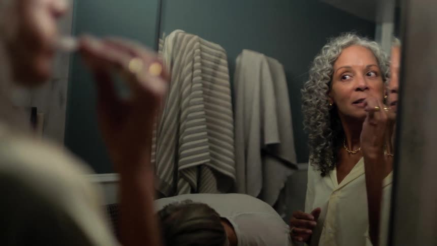 A man and woman brush their teeth at the same time in a bathroom