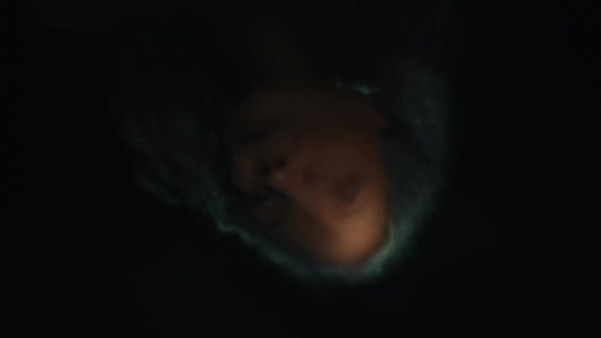 The head of a woman with gray hair is reflected in the surface of water