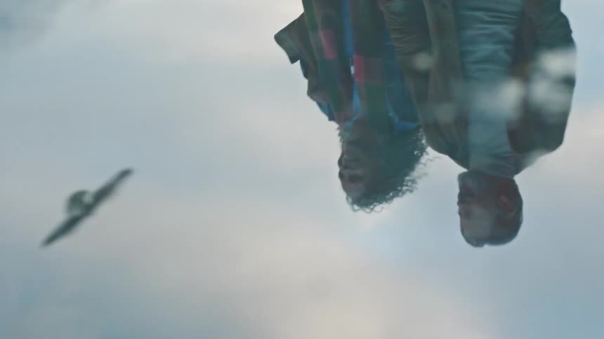 Reflection of two people walking appears upside down on a puddle of water