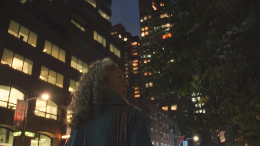 A woman walking down a sidewalk in a city
