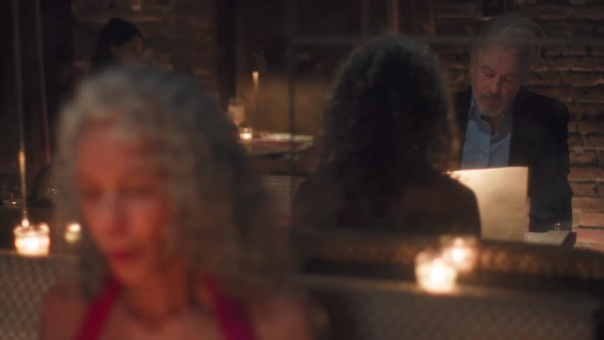 A woman and a man are in a restaurant looking at the menu and there are some candles beside them