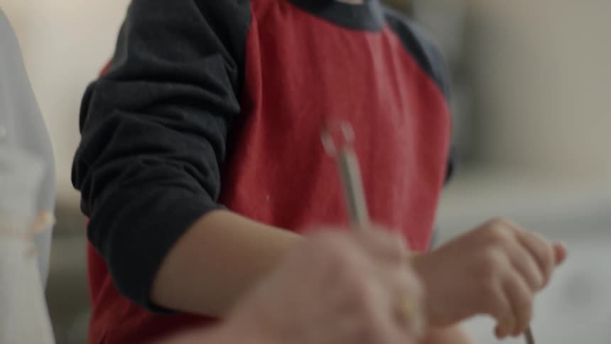 A boy and elderly woman stir batter with whisks
