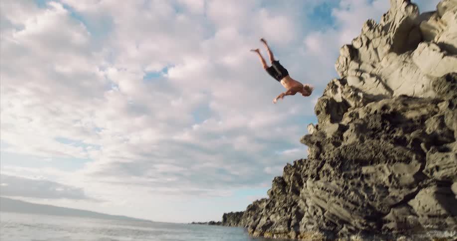 A man diving off a cliff into water