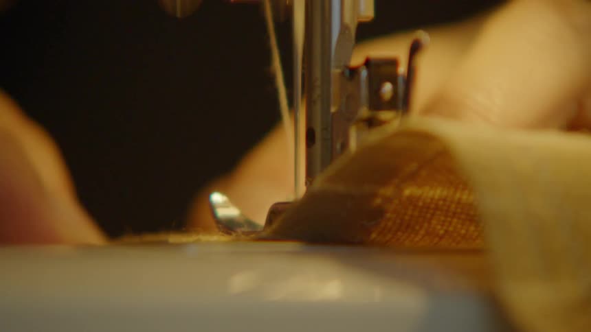 Sewing machine needle stitches fabric in a closeup view