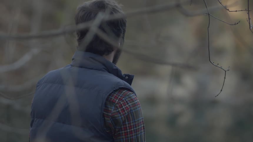 Bearded man looking at a secluded lake in the woods