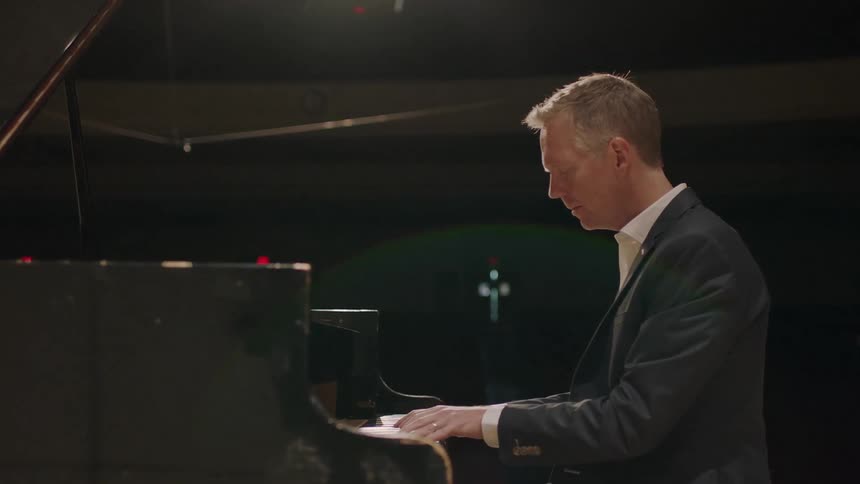 A man is playing the piano in a dark hall
