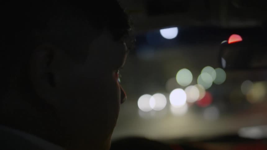 A man drives a car in a city at night