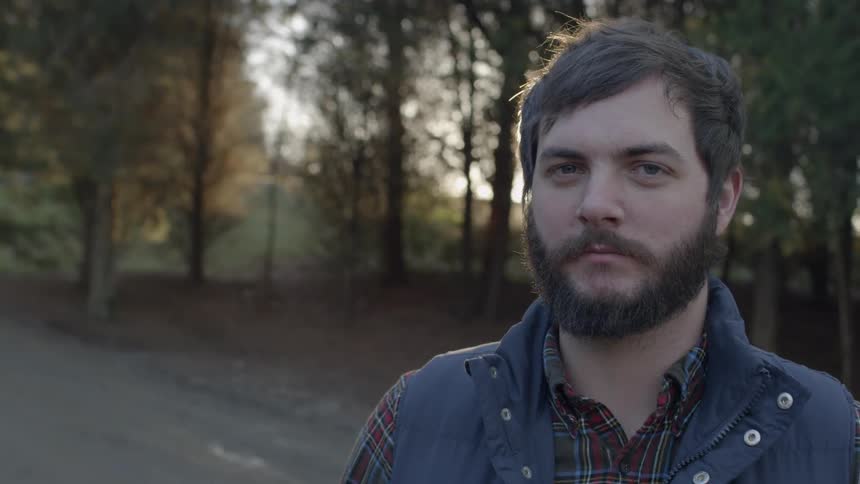 Bearded man in front of some trees at sunset