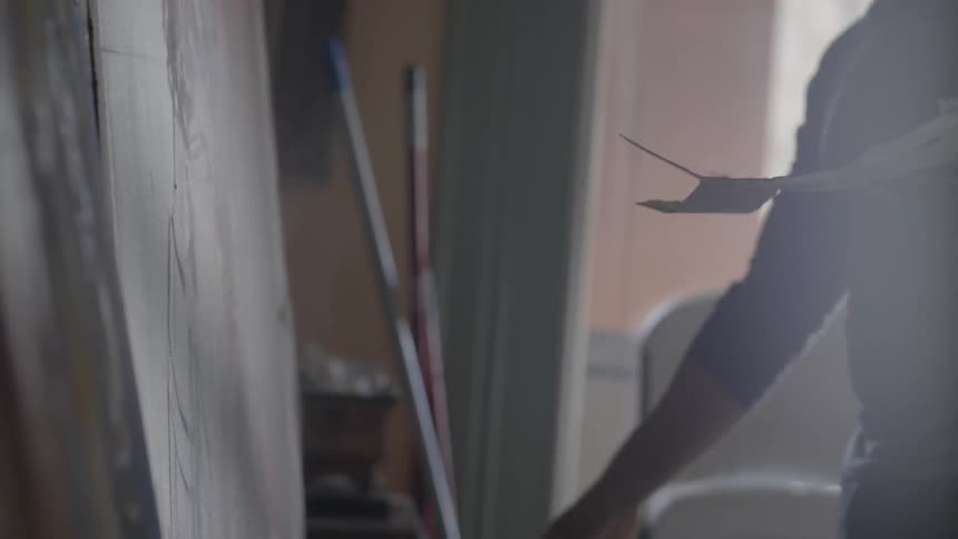A bearded man sprays a canvas with water