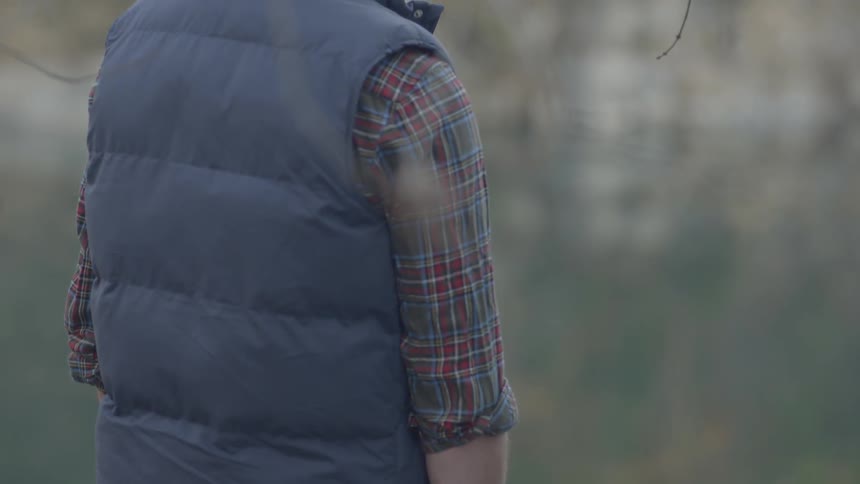 Man standing lakeside wearing a vest
