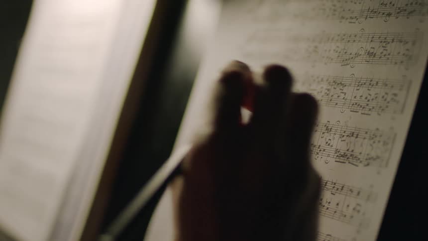 A person edits notes on sheet music