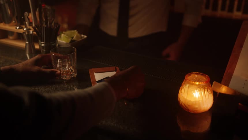 Customer puts a credit card on top of his bar tab and the bartender puts it in a processing machine