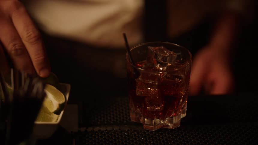 Bartender adding garnish and a straw to a drink