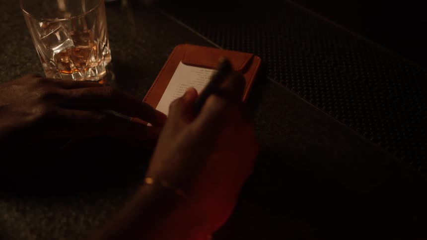 A persons hand using a pen to write on a receipt that is on a table