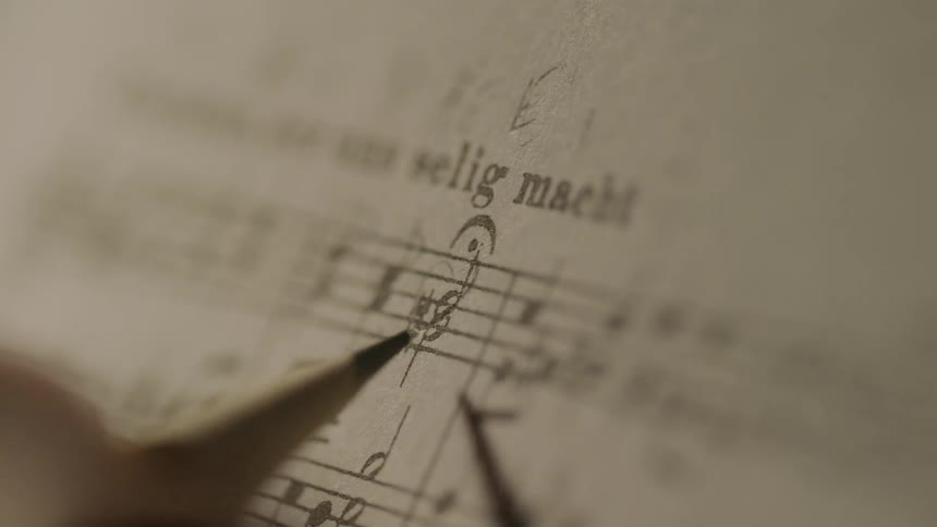 A person writes on sheet music