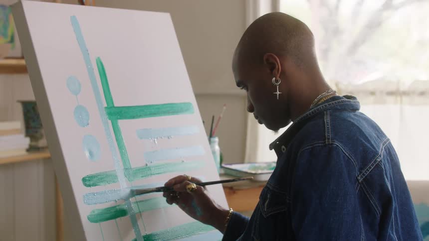 A man painting in a room on a canvas