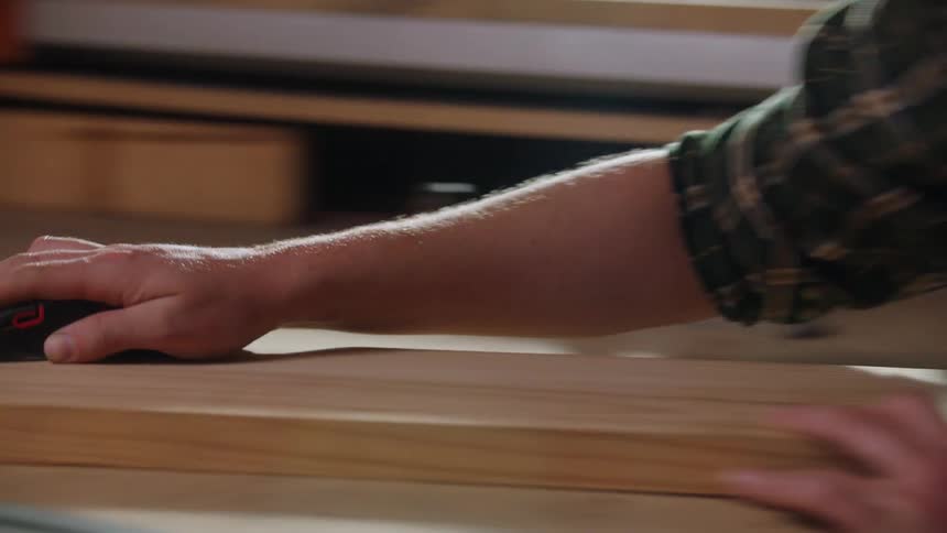 Hand sanding wood surface with sanding block in woodworking setting