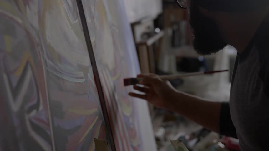 A man paints on a large canvas