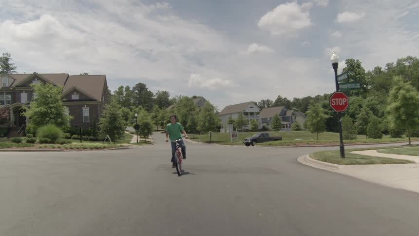 A boy is riding his bicycle in a neighborhood