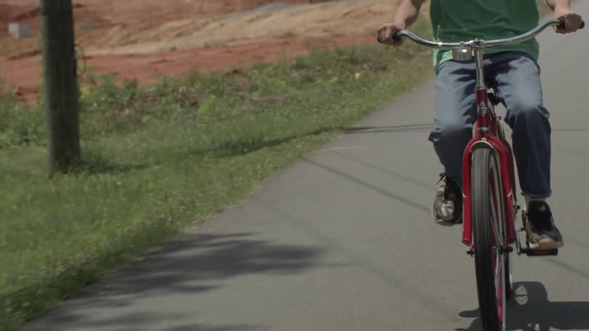 A boy is riding his bicycle on the road
