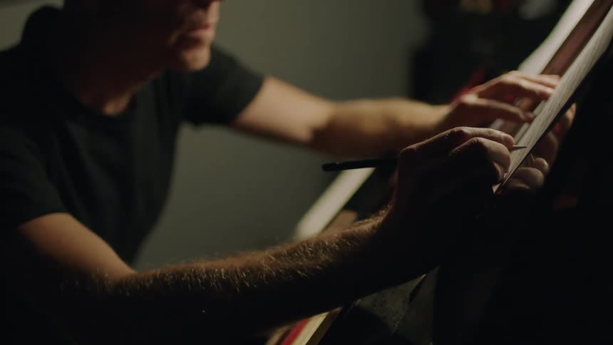 A man is playing the piano and writing