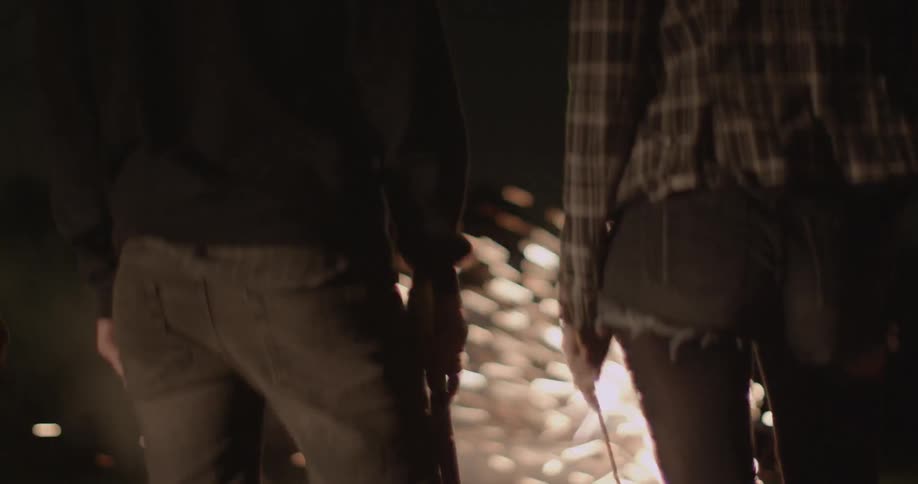 People stand around at night watching fireworks