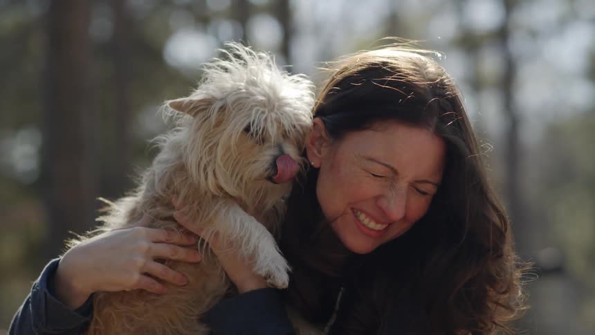 A dog looks a woman's face while she smiles
